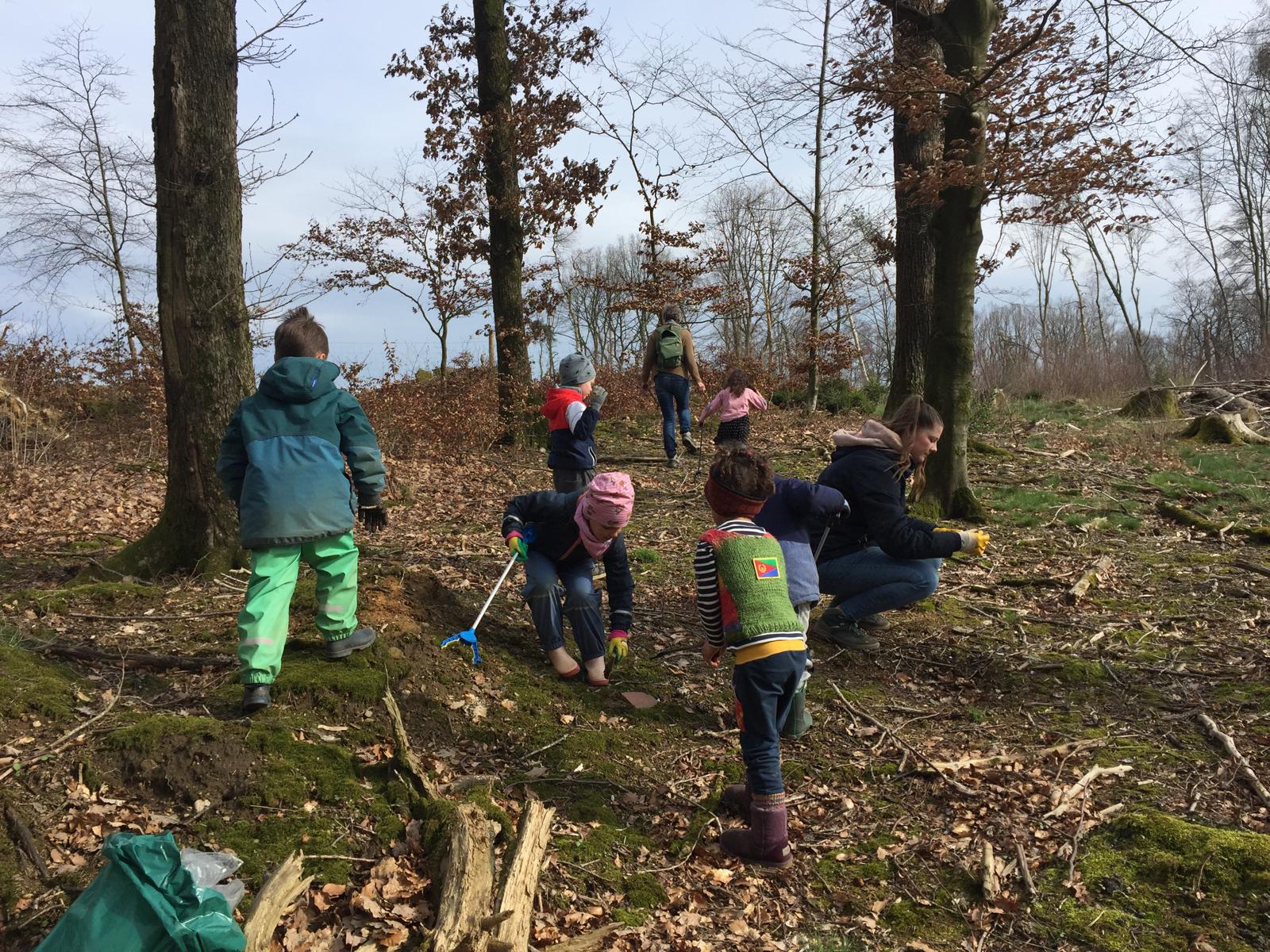 Kinder sammeln Müll ein im Wald.