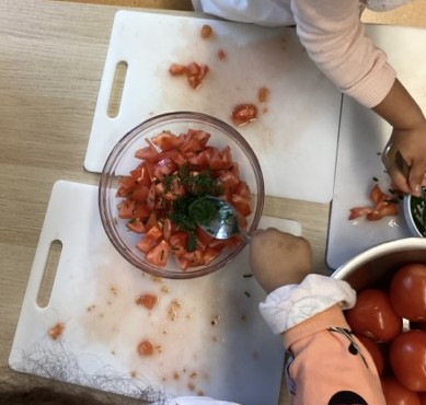 Kinder verfeinern den Tomatensalat mit eigenen Kräutern.