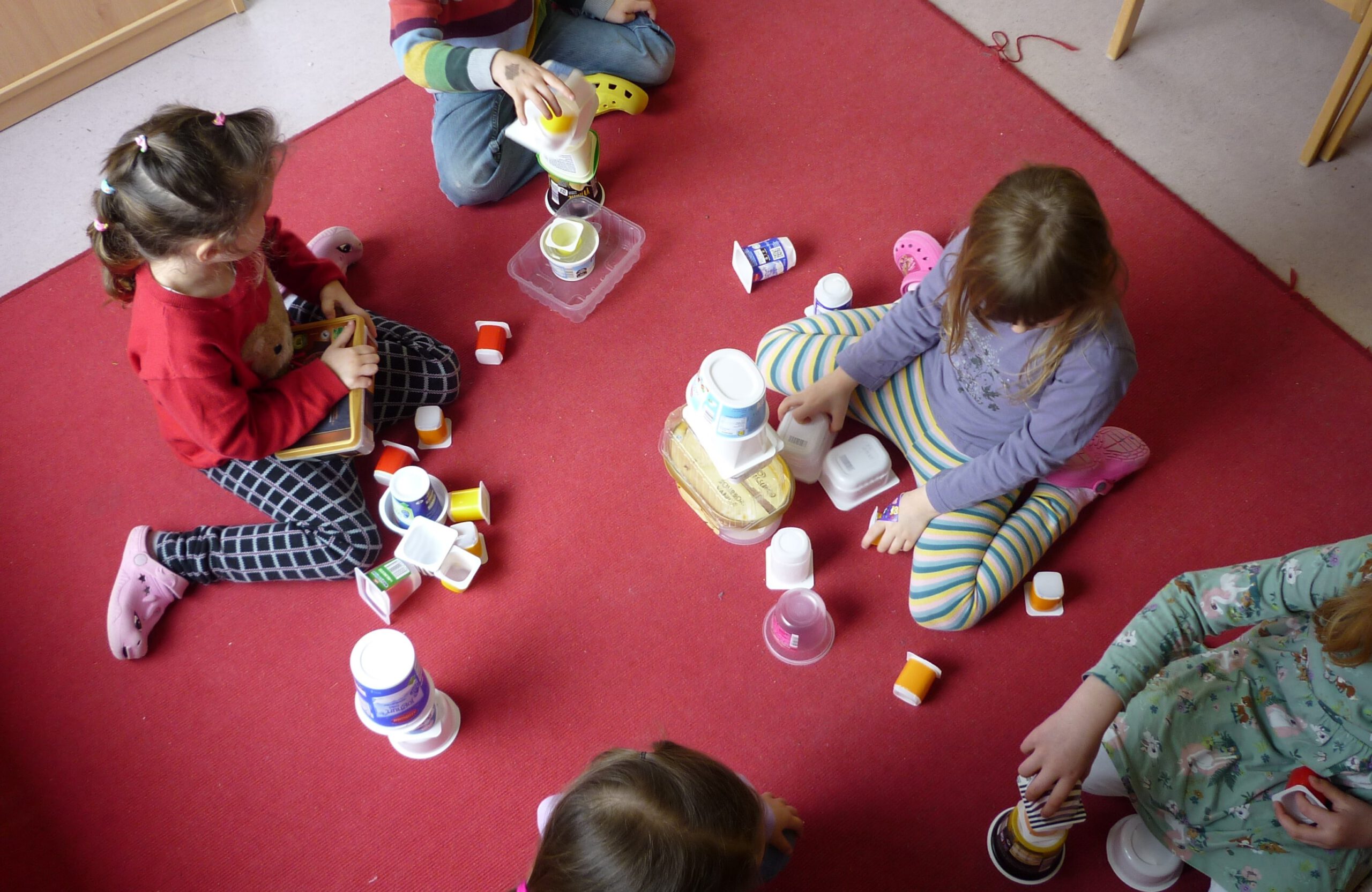 Kinder spielen mit Joghurtbechern