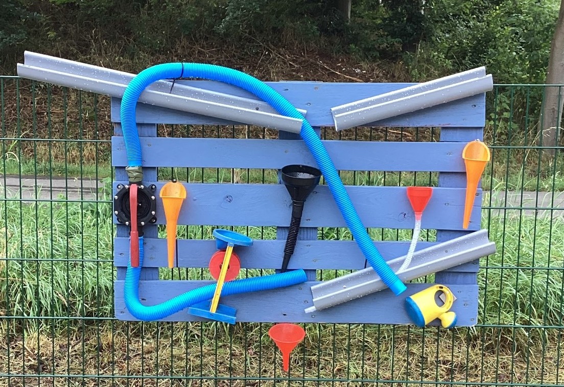 Ein selbstgebauter Wasserlauf aus Rohren und einer Mühle
