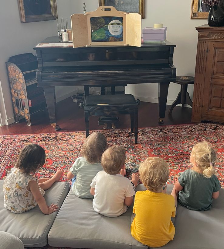Die Kinder schauen auf ein Kamishibai der Raupe Nimmersatt