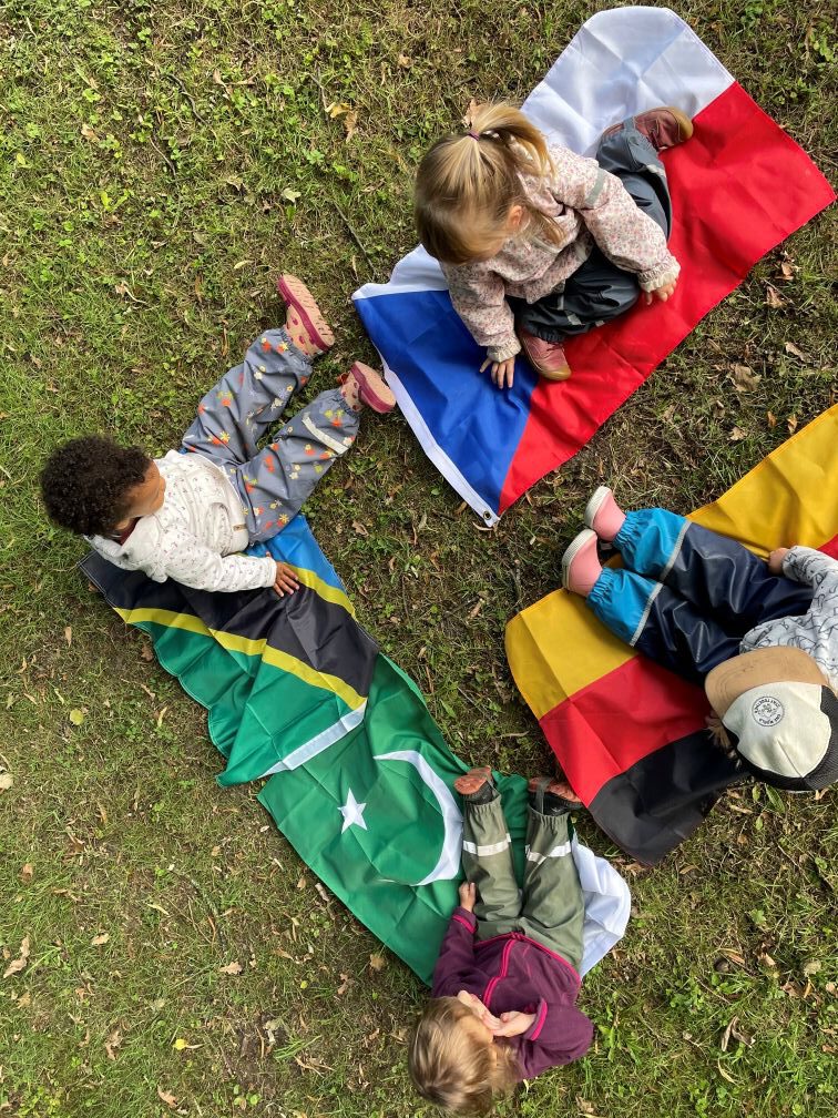 Kinder sitzen auf verschiedenen Landesflaggen
