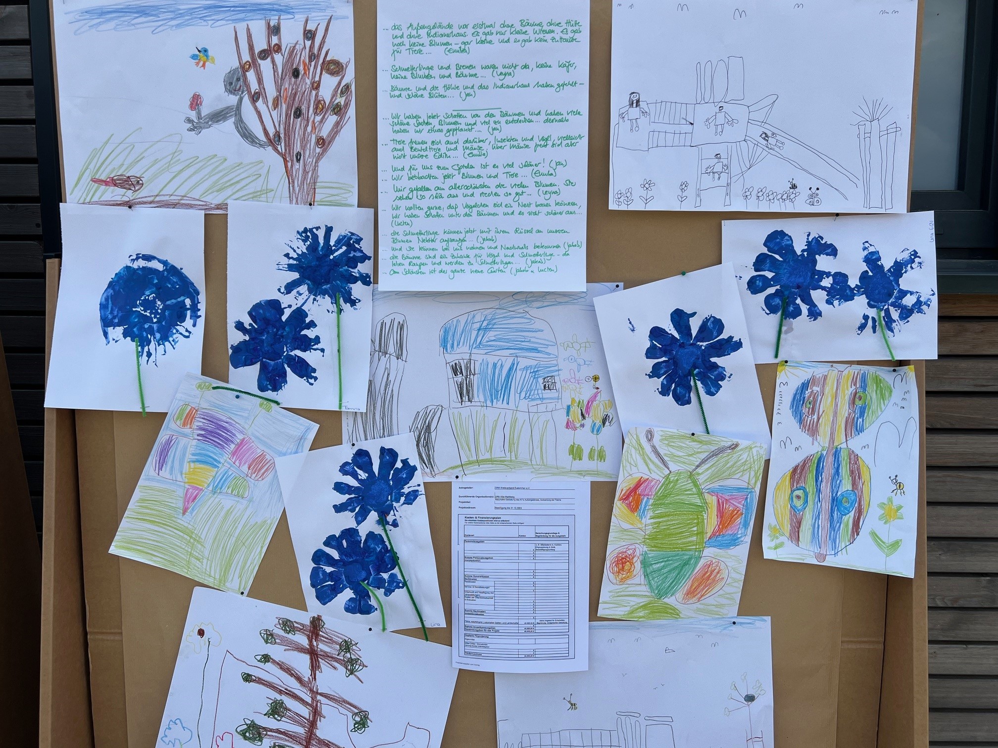 An der Pinwand hängen Kinderkunstwerke zu Insekten, Bäumen und anderen Lebewesen