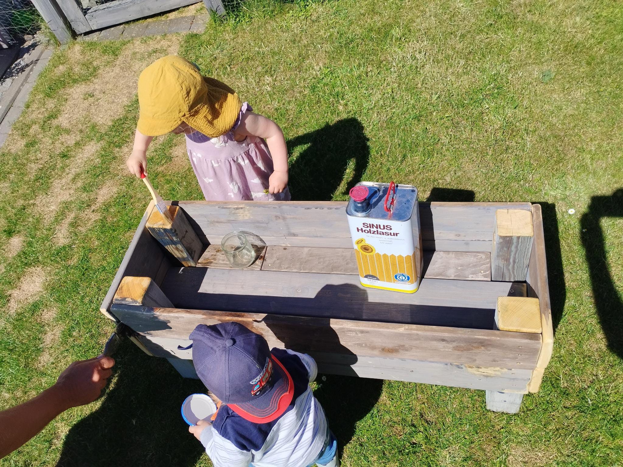 Kinder streichen einen selbstgebauten Pflanzkasten.