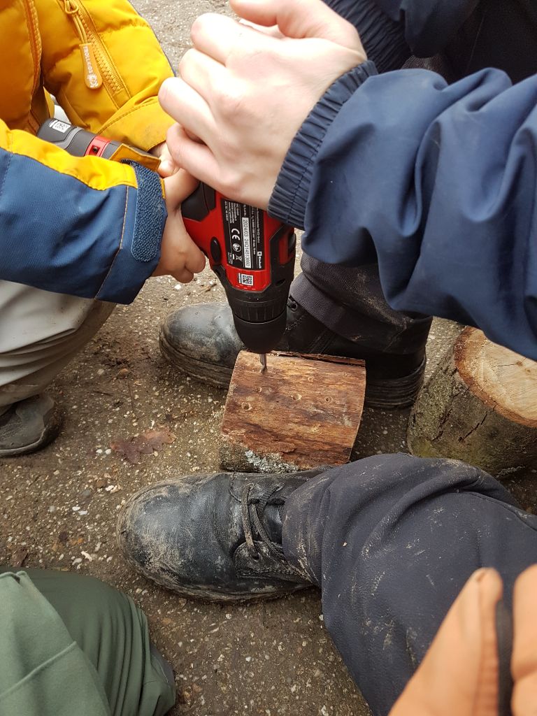 Die Kinder bohren Löcher ins Holz.