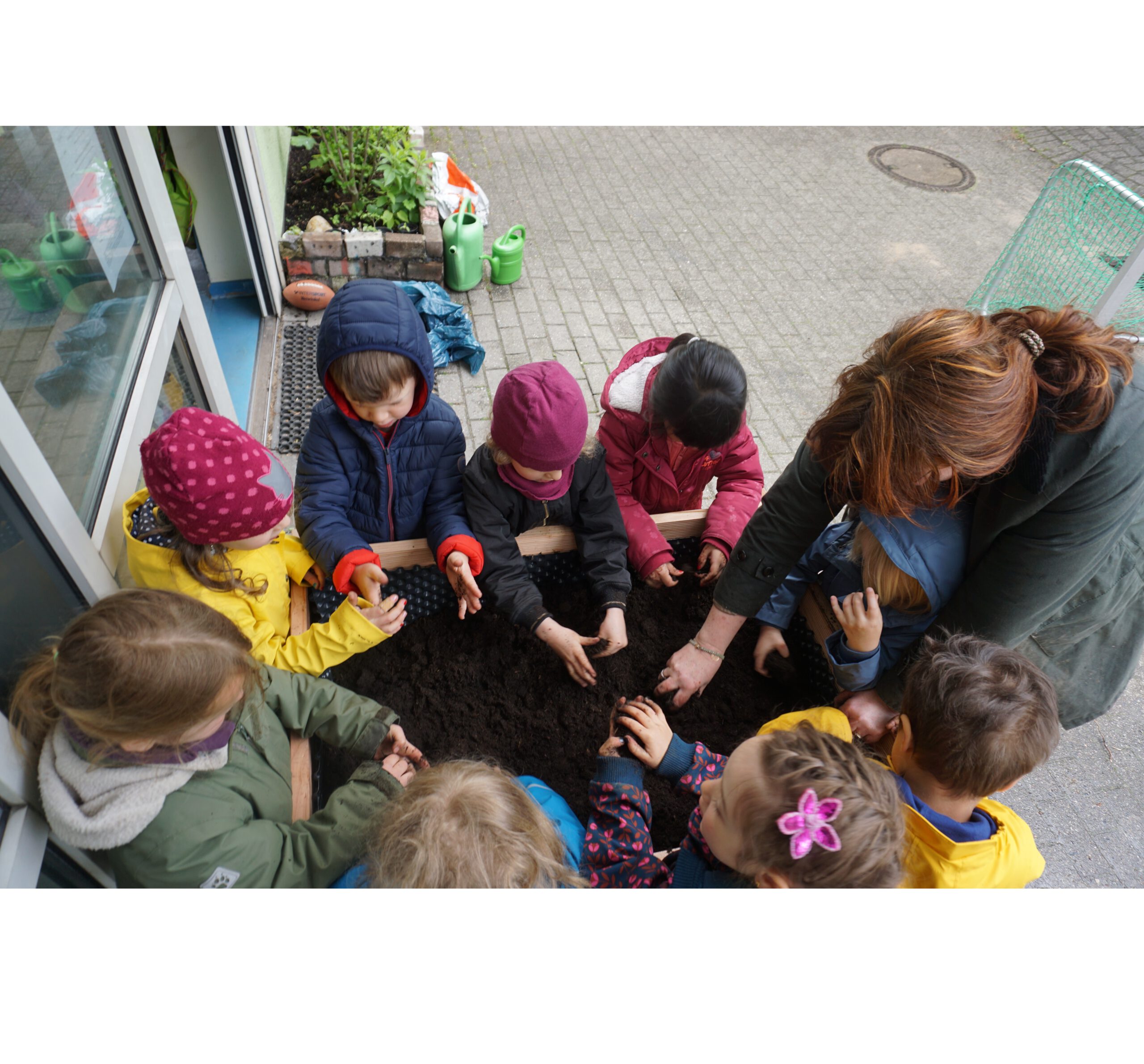 Kinder arbeiten an einem Hochbeet.