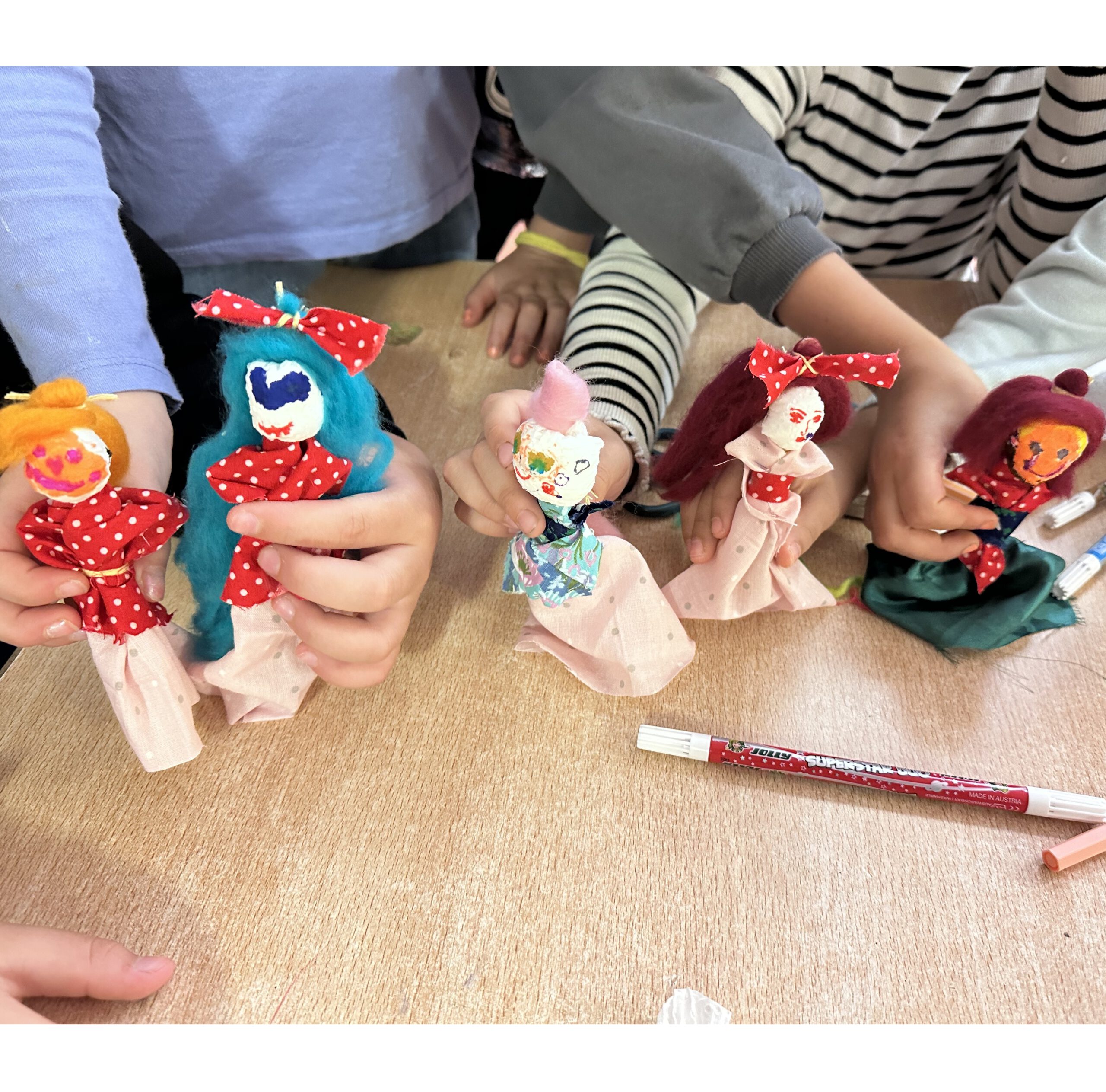 Kinder präsentieren ihre selbstgebastelten Püppchen