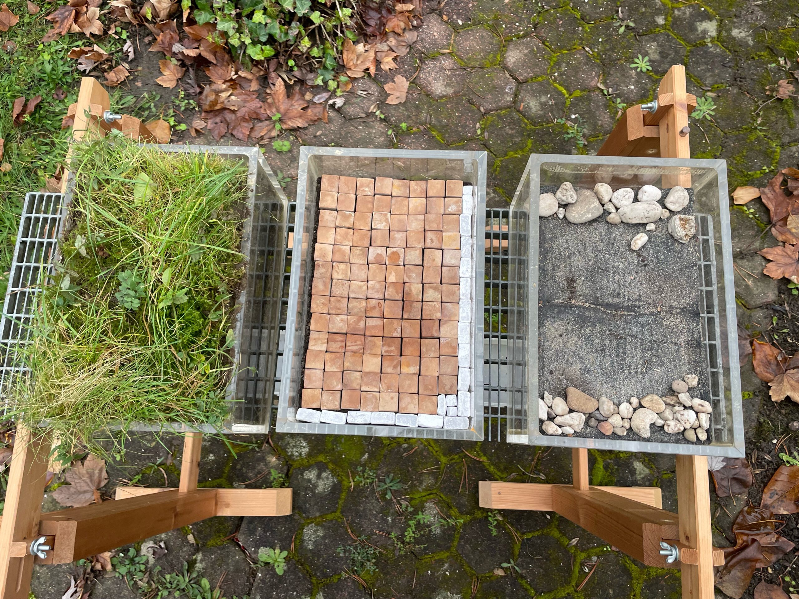 Drei Kästen mit unterschiedlichen Bodenbelägen - Gras, Steine und Dachpappe